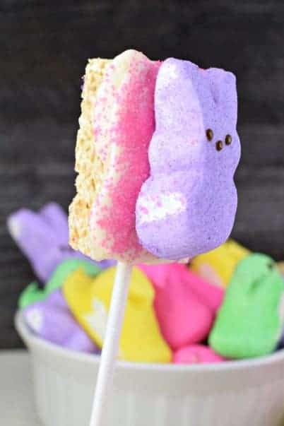 Rice Krispie Treat on a stick with melted white chocolate, pink sanding sugar, and a purple bunny Peep.