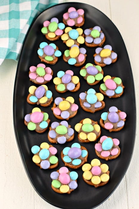 Black oval plate with candy made of pretzel twists, chocolate, and M&M's candies.