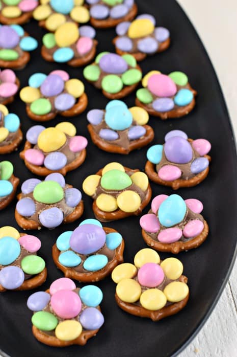 Black plate with pretzels and M&M's candy to make spring flowers.