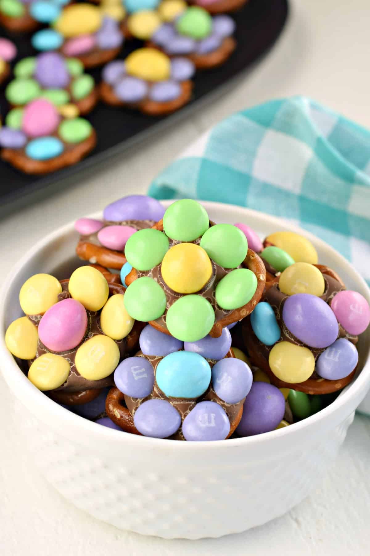 White bowl with pretzel twists and melted hershey kiss and pastel m&ms to make a flower.