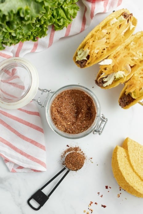 Taco seasoning in a jar with a teaspoon scooped.