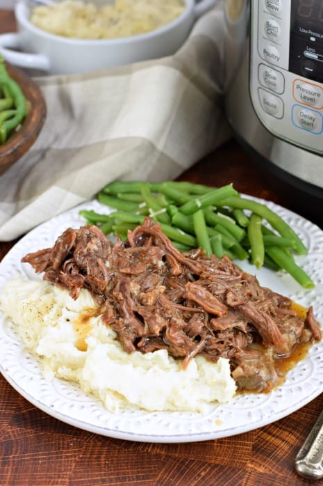 Balsamic roast beef on plate with mashed potatoes and green beans. Instant Pot in background.