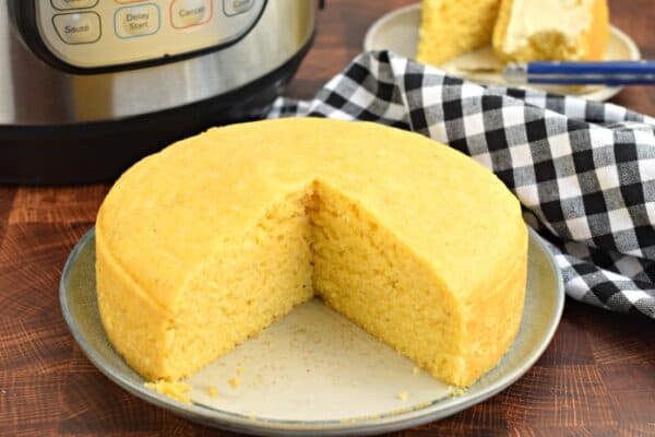 Corn bread on plate with pressure cooker in background.