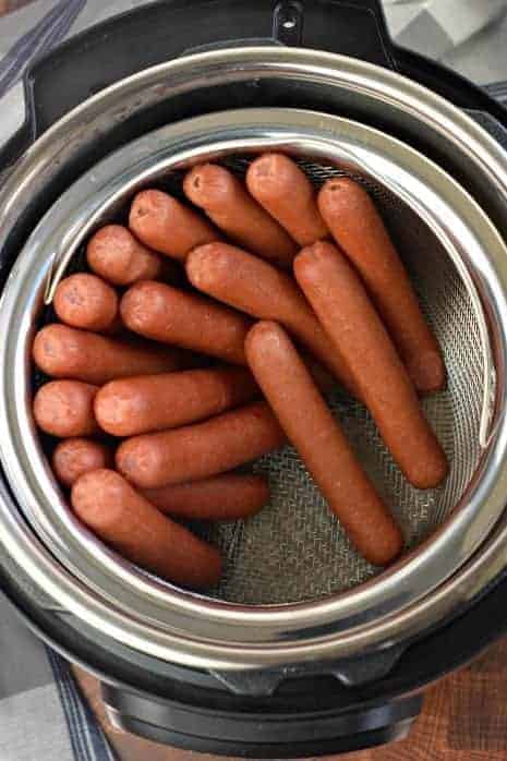 Instant Pot filled with a steamer basket of cooked hot dogs.