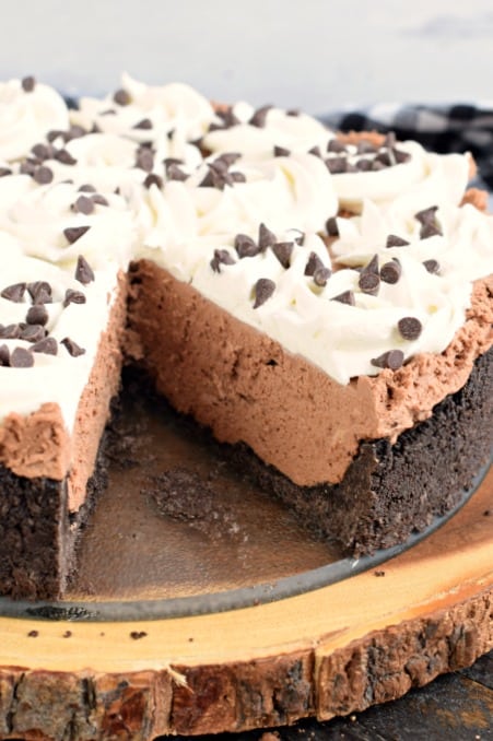 Whole chocolate cheesecake with one slice removed.