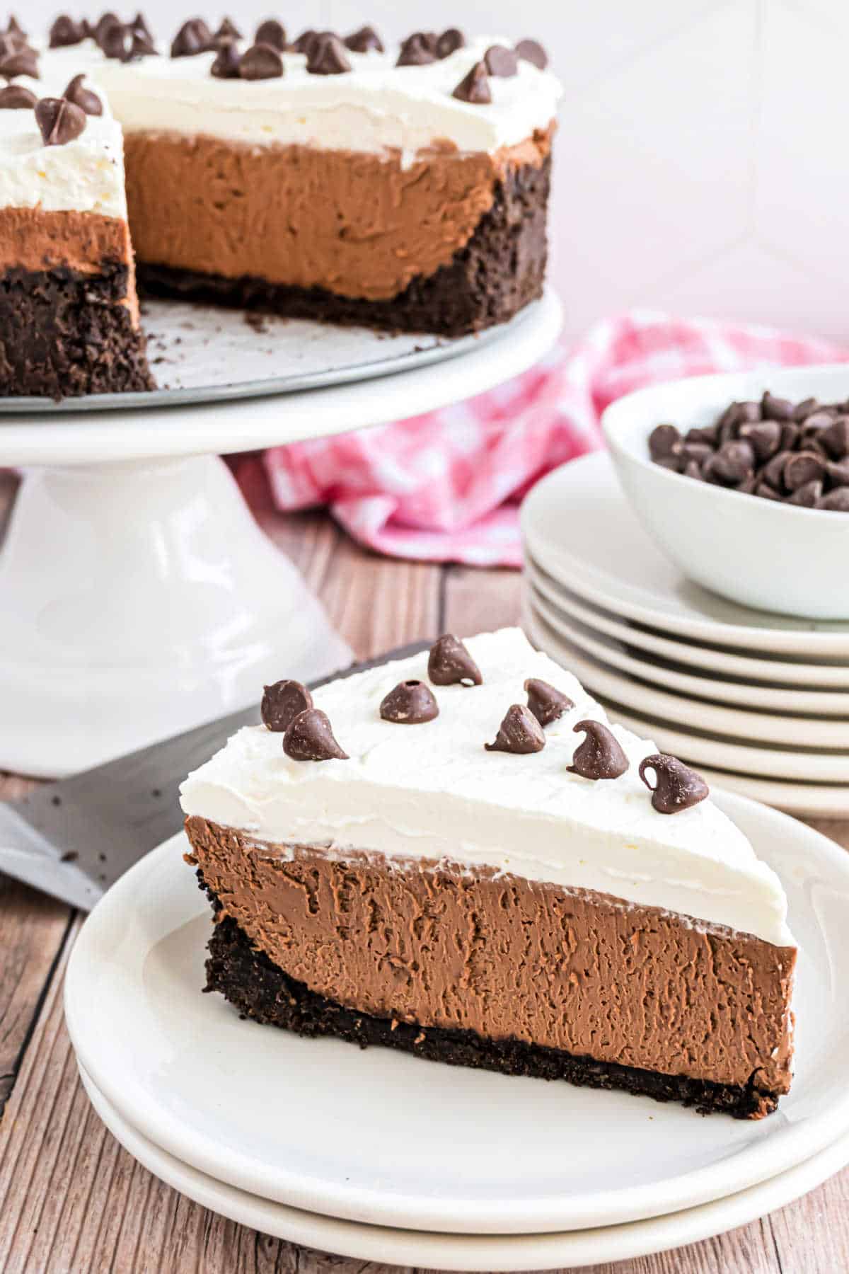 Slice of chocolate cheesecake on a stack of white plates.