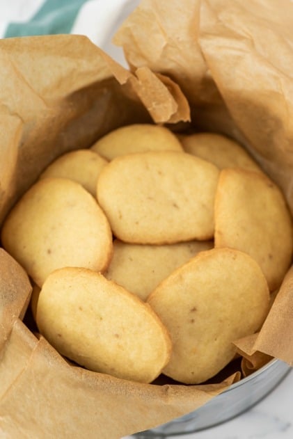 Round tin of shortbread cookies with parchment paper.
