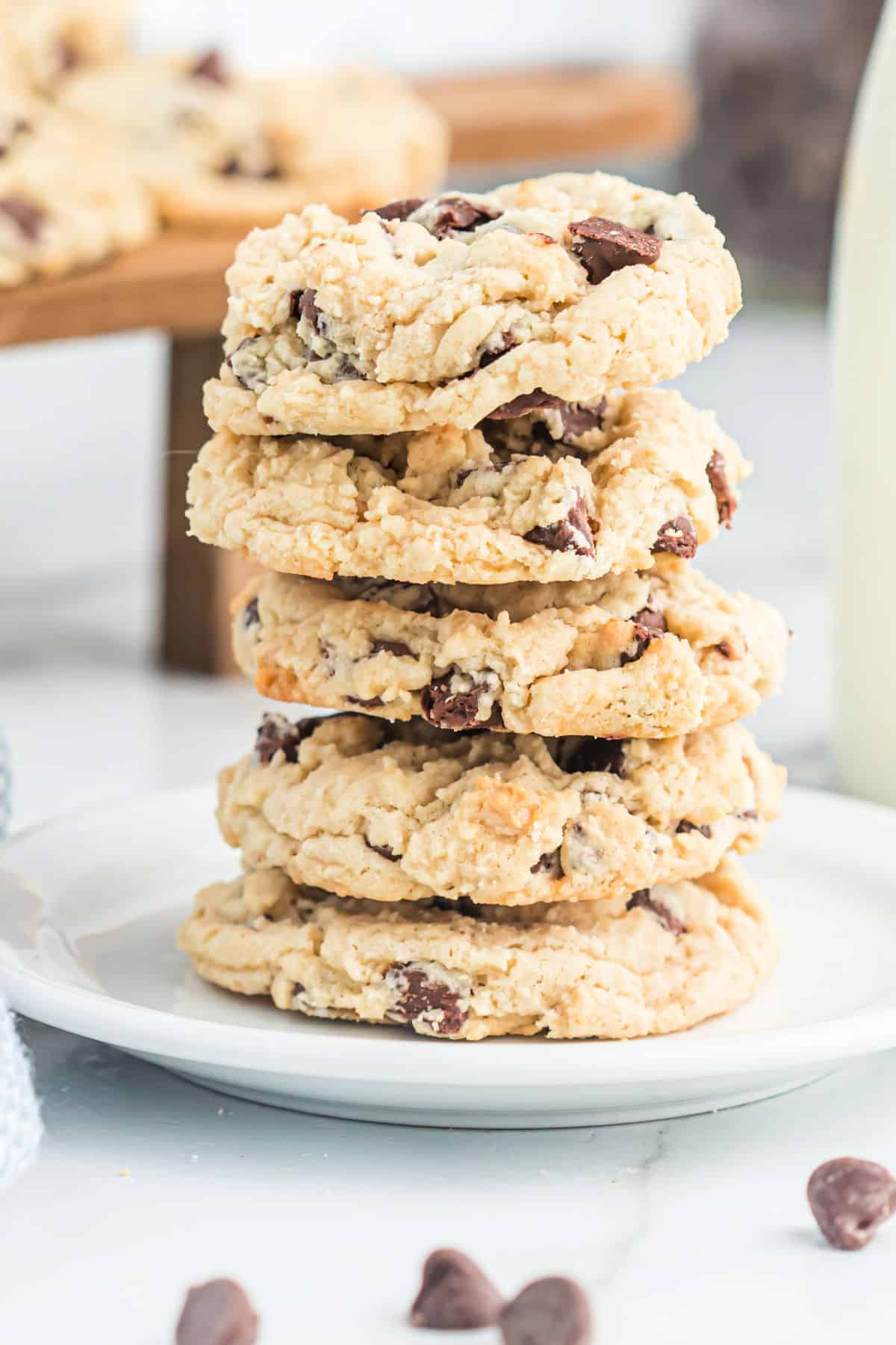 Chocolate chip cookies stacked on a white plate.