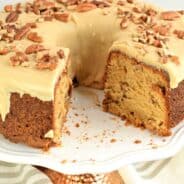 Brown sugar pound cake with caramel glaze on a white cake plate with a big chunk removed.