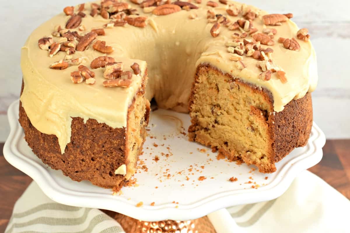 Brown sugar pound cake with caramel glaze on a white cake plate with a big chunk removed.