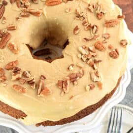 Brown Sugar Pound Cake topped with caramel glaze and pecans on a white cake platter.