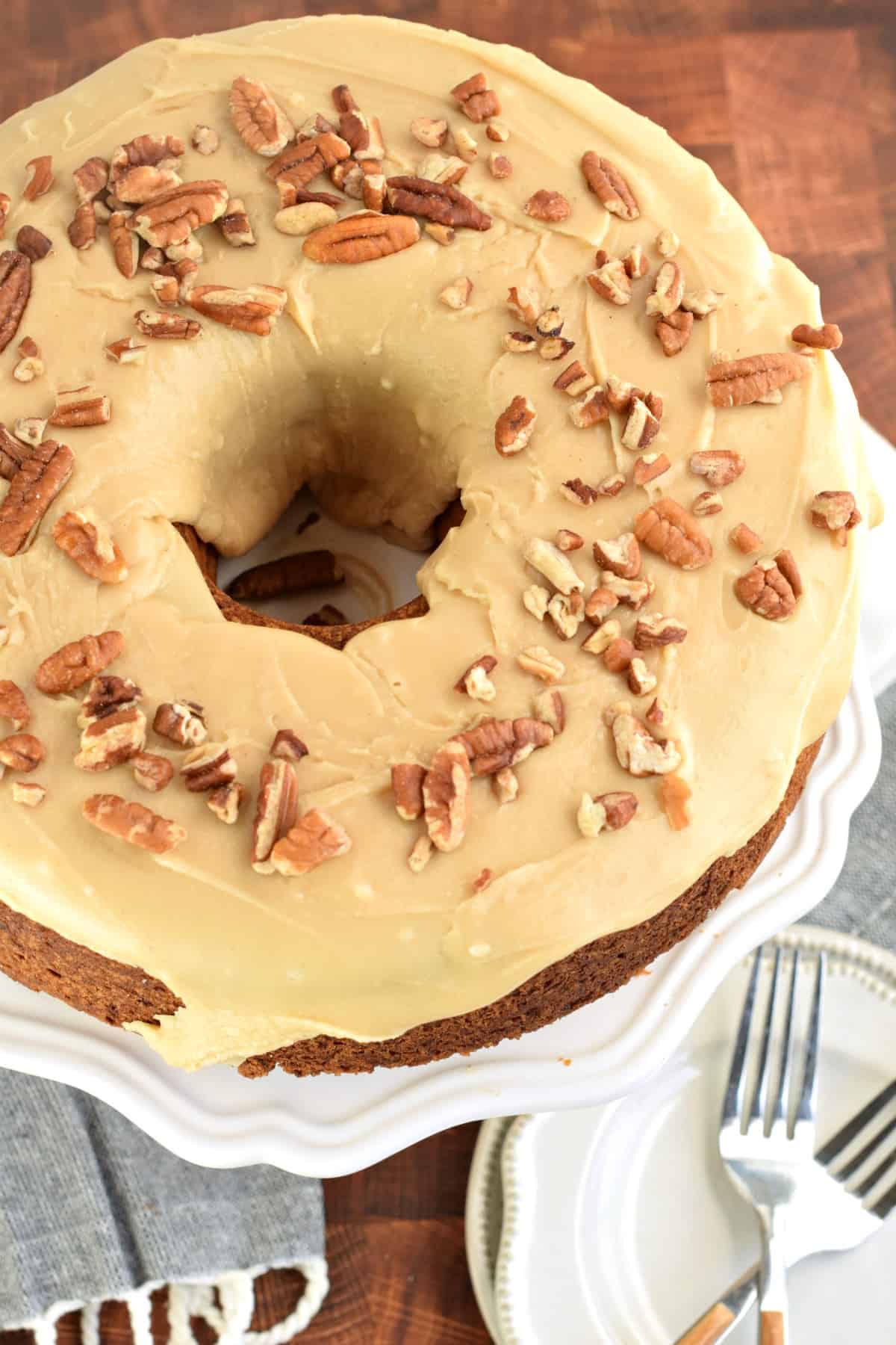 Brown Sugar Pound Cake topped with caramel glaze and pecans on a white cake platter.