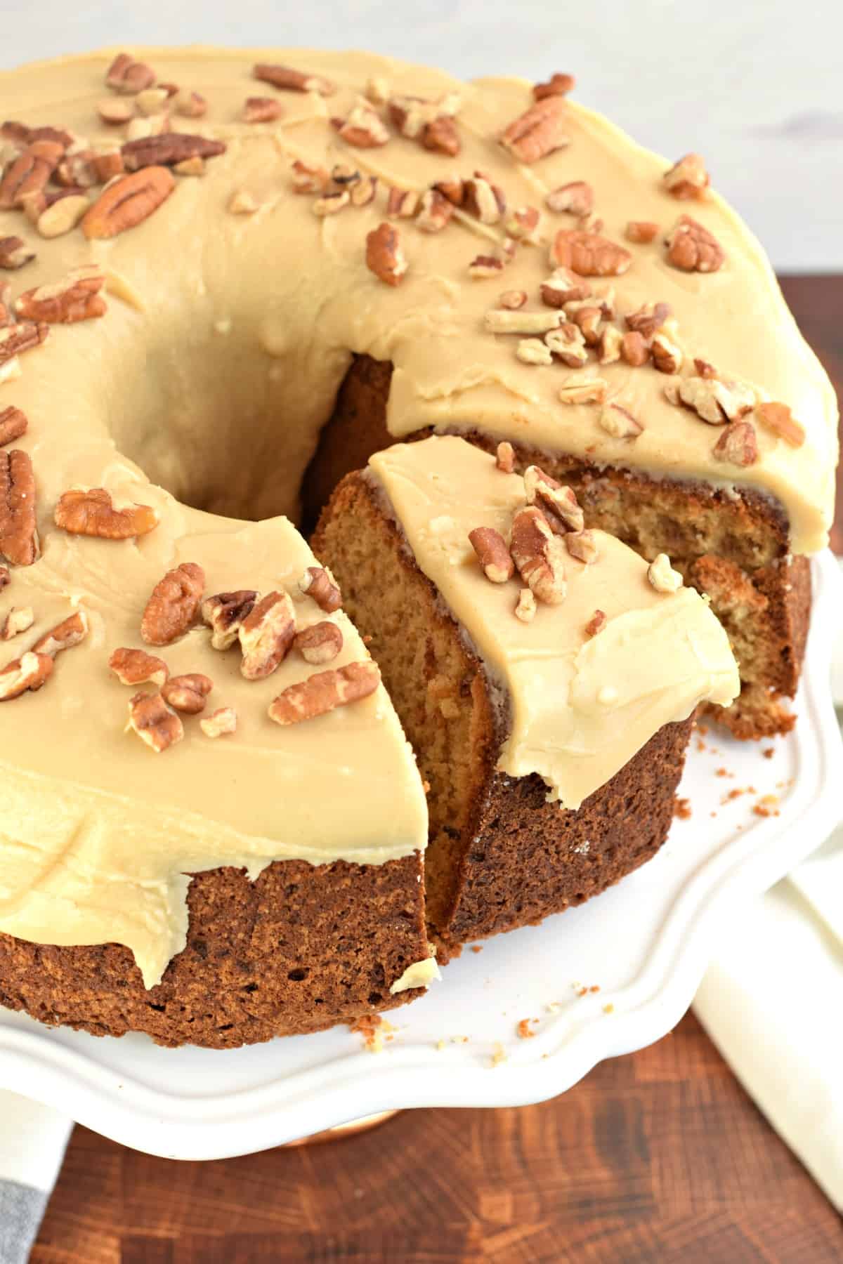 Whole pound cake on a white cake plate with one piece sliced and ready to remove.