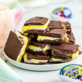 Stack of cadbury egg fudge cut into squares and served on a white plate.