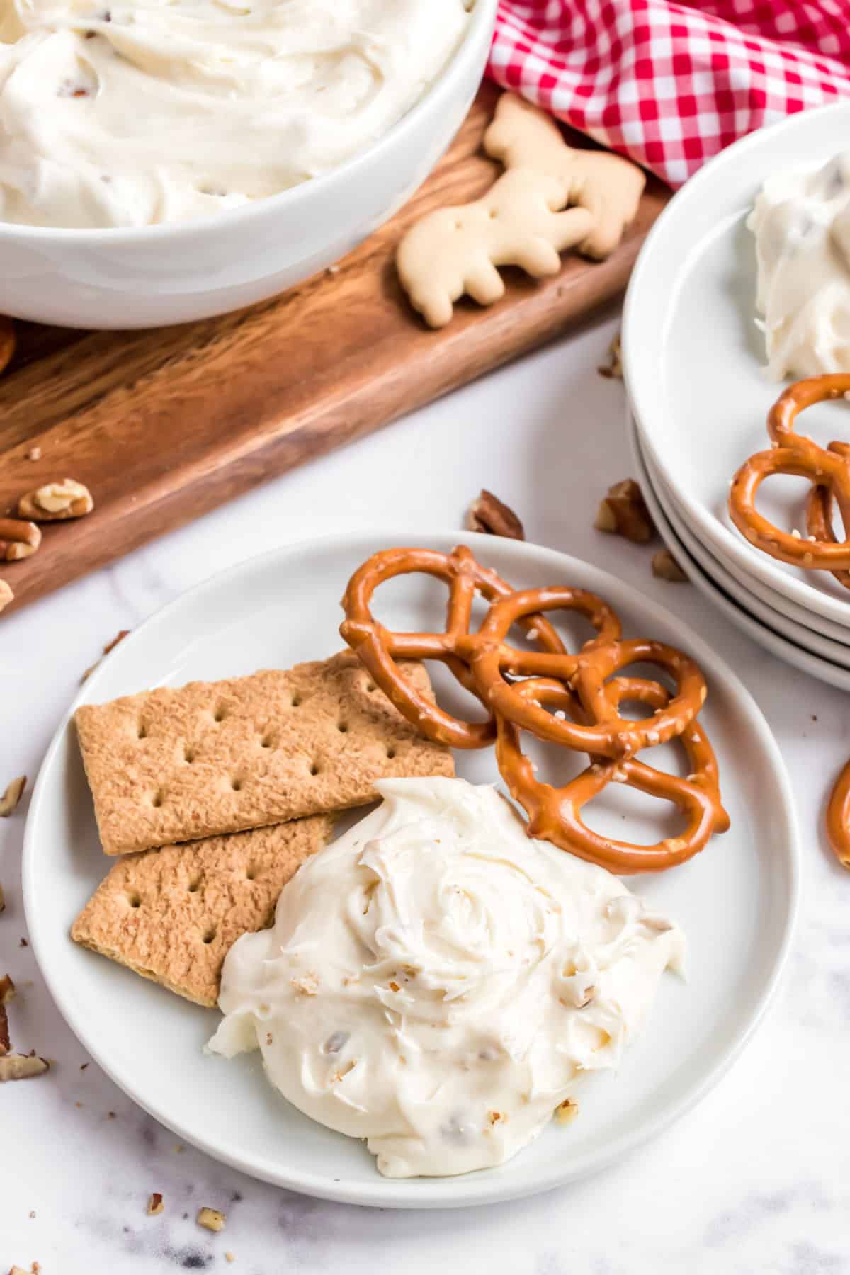 Cheesecake dip scooped onto a white plate with graham crackers and pretzels.