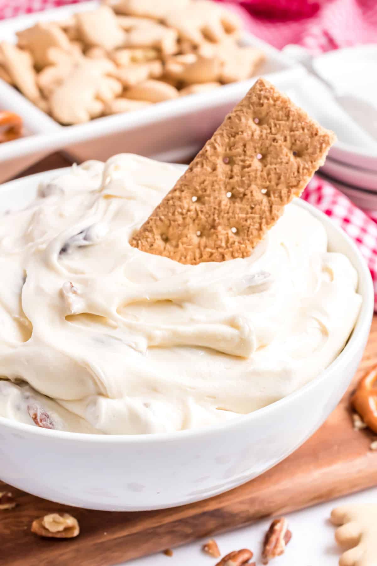 Cheesecake dip in a white bowl with a graham cracker dipper.