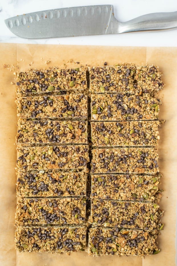 Parchment paper with cut granola bars and knife at top.