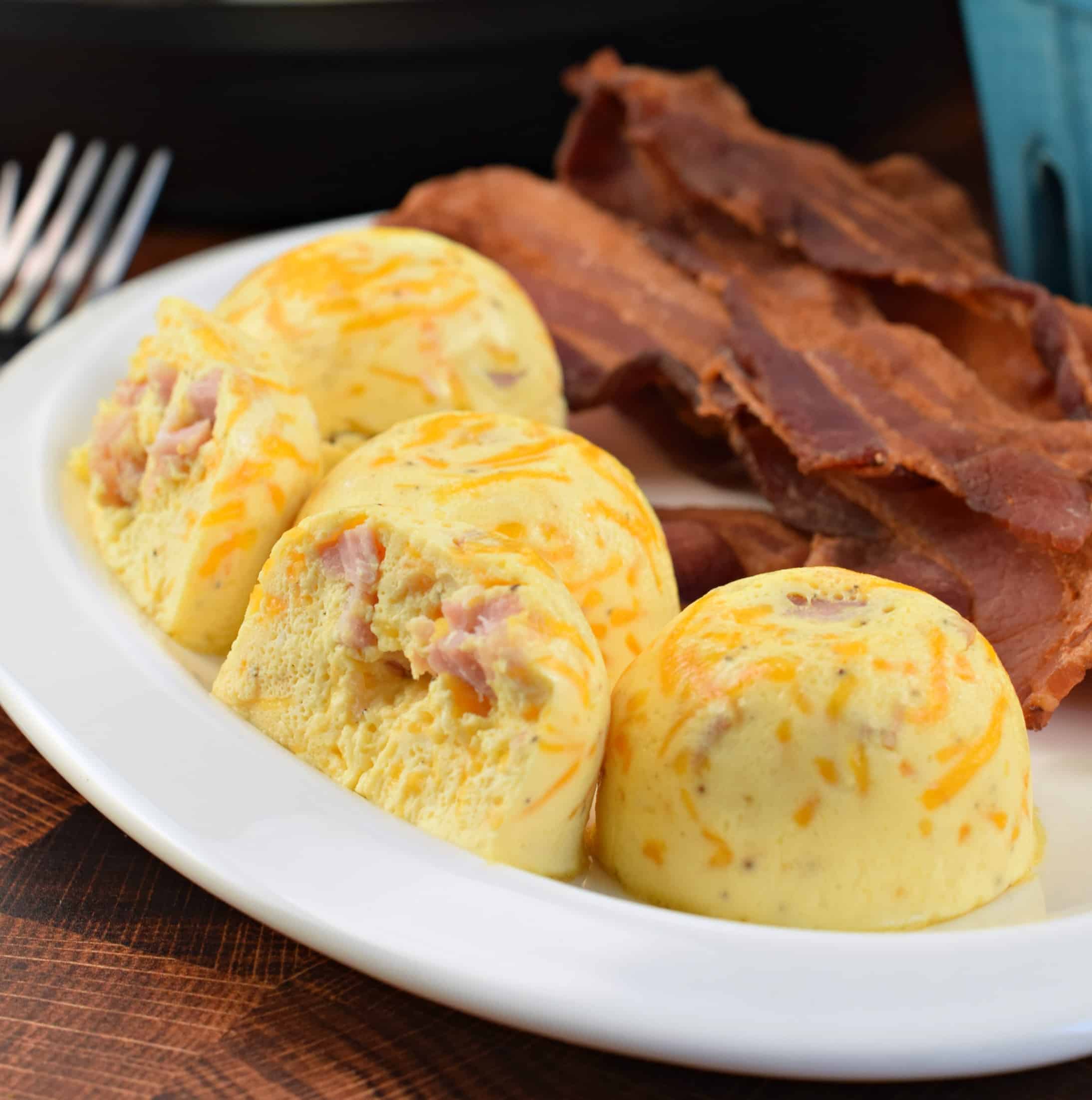 Ham and Cheese egg bites made in the Instant Pot with cooked bacon on a white plate.