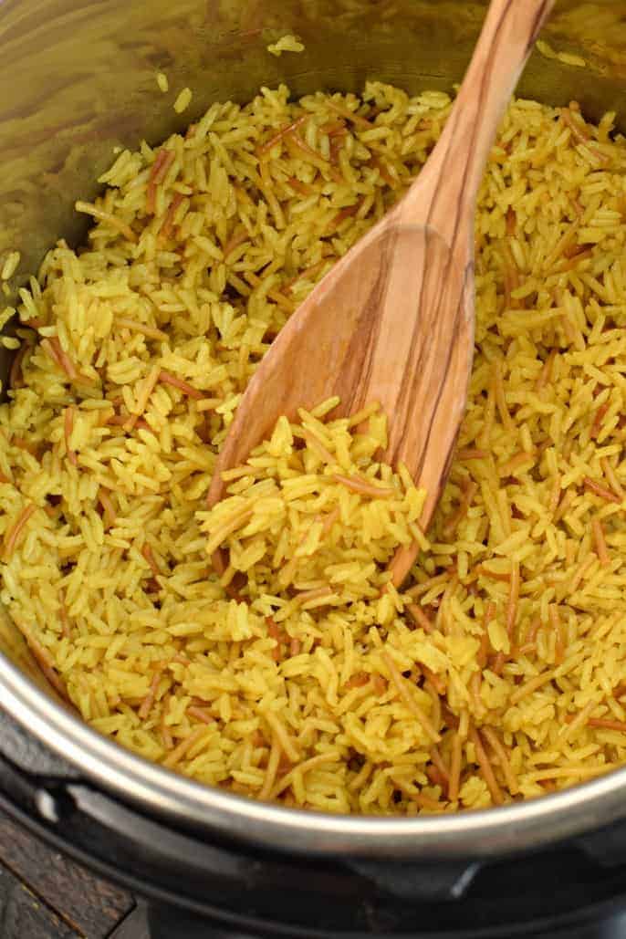 Silver pot filled with homemade Rice a Roni served with a wooden spoon.