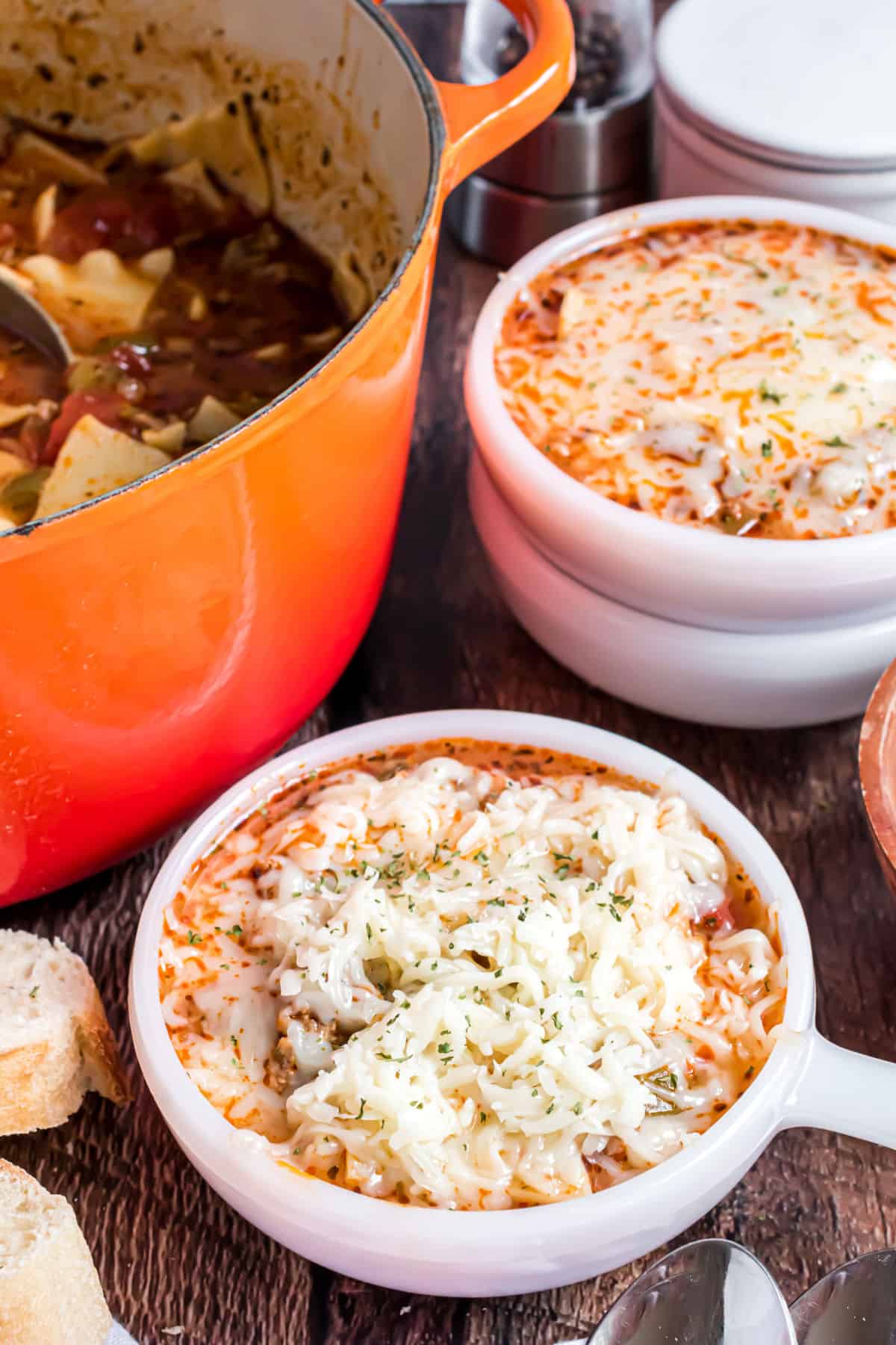 Two bowls of lasagna soup with a pot of soup in background,