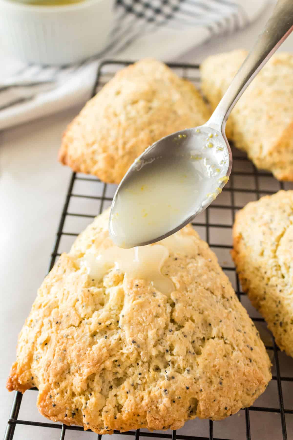 Lemon glaze being spooned over cooled lemon poppy seed scones.