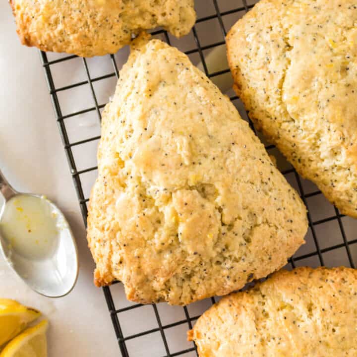 Lemon poppy seed scone on wire cooling rack with fresh lemon glaze.