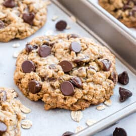 Oatmeal chocolate chip cookie baked on a parchment paper lined cookie sheet.