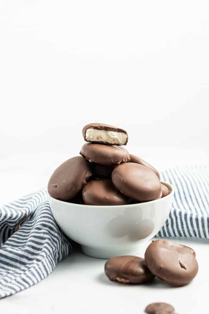 Blue striped napkin with white bowl piled high with peppermint patties.