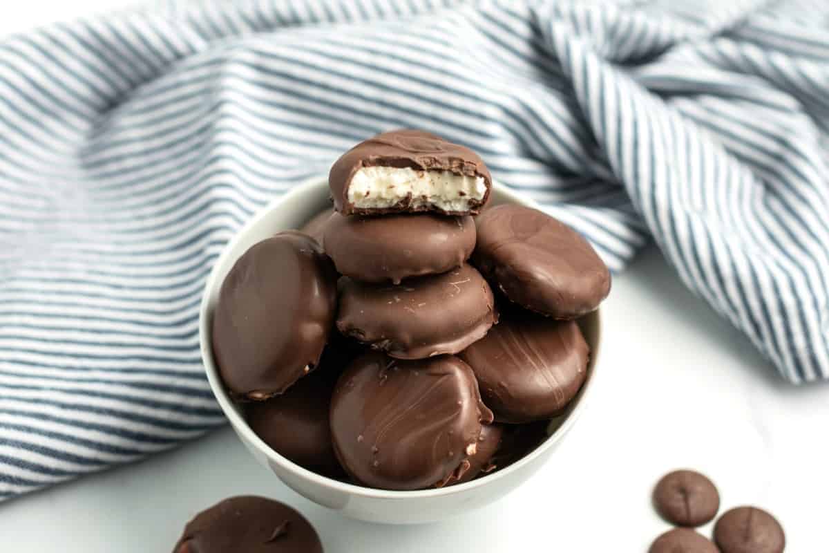 White bowl on a blue striped napkin filled with homemade peppermint patties.