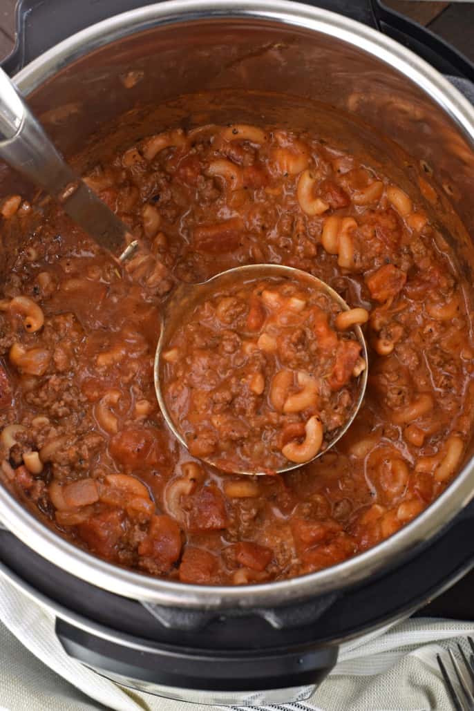 American goulash with tomato, beef, and elbow noodles in an Instant Pot with a silver ladle.