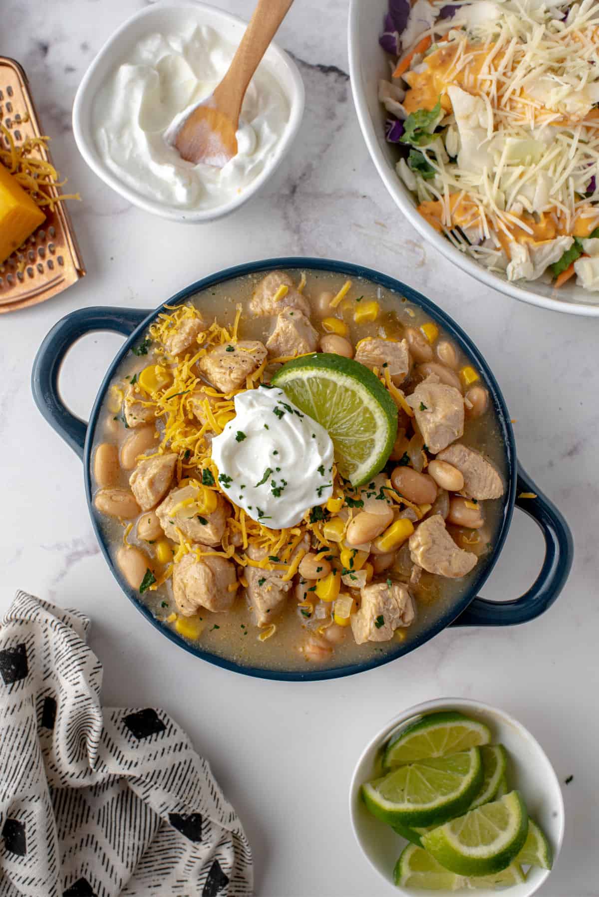 White chicken chili in a bowl with cheese and sour cream toppings.