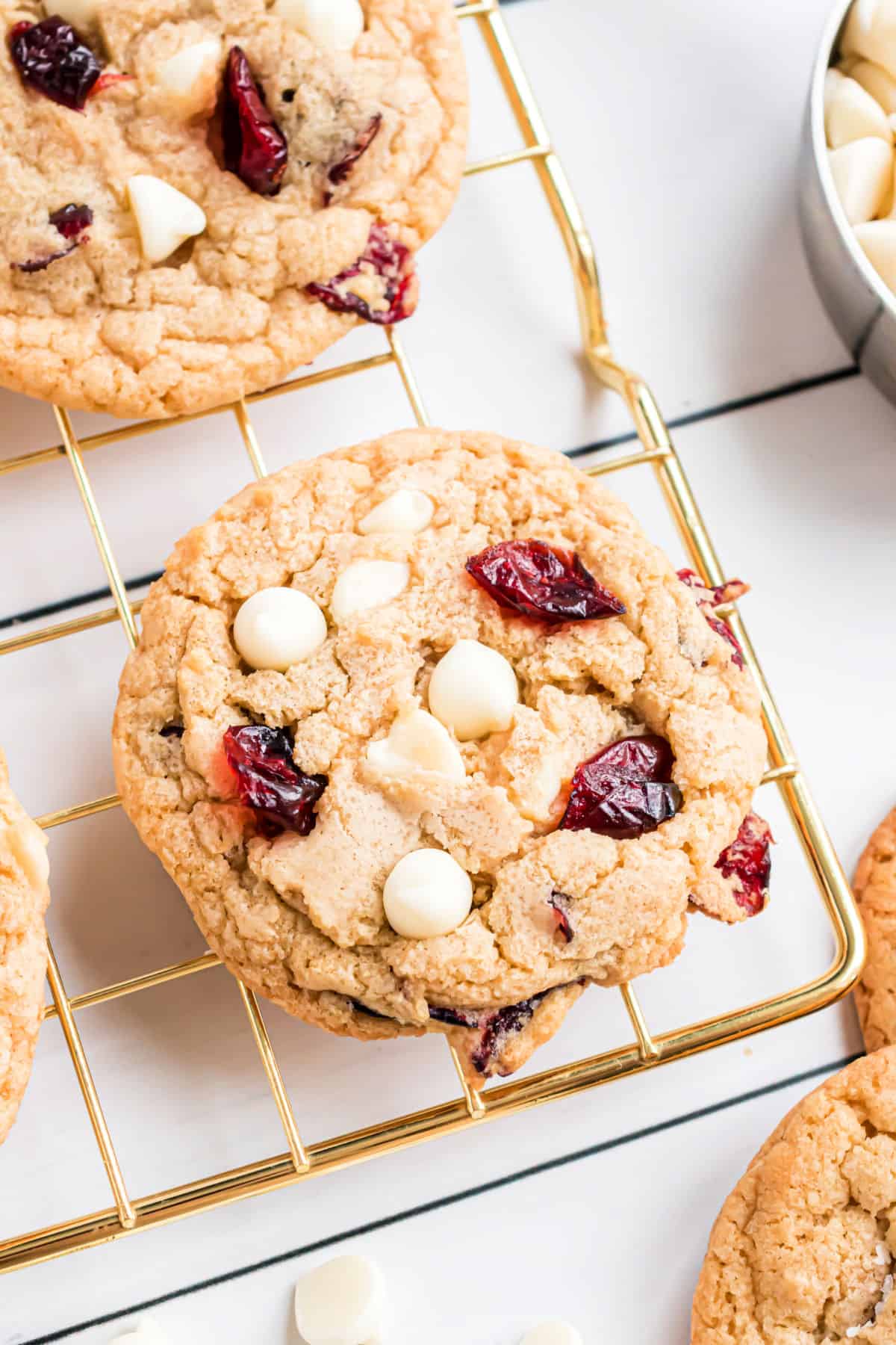 White chocolate cranberry cookie on a gold cooling rack.