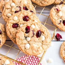 Stack of white chocolate cranberry cookies on wire cooling rack.