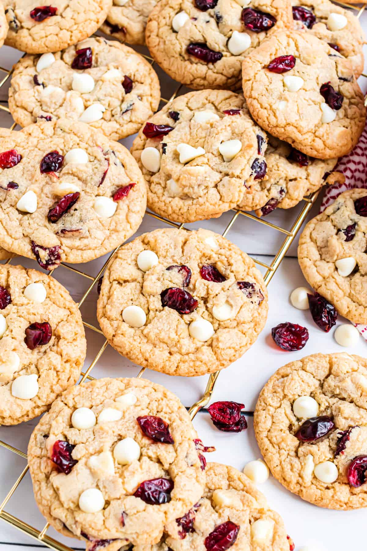 Cookies with white chocolate chips and craisins on a wire cooling rack.