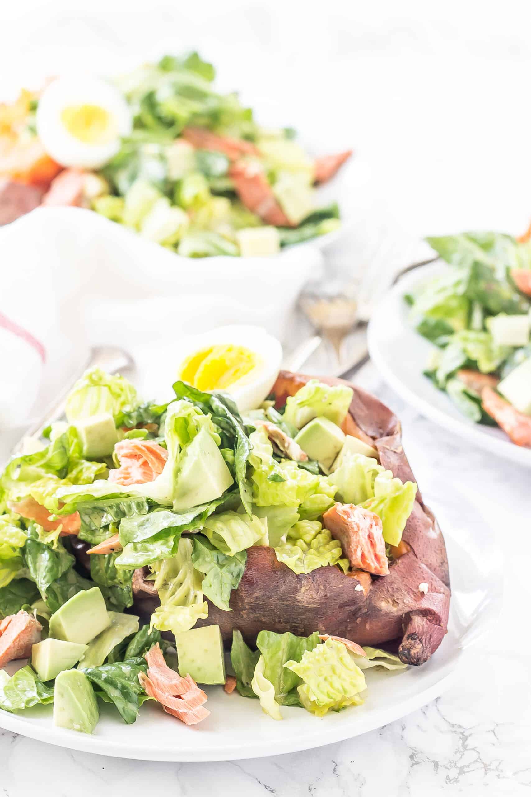 Homemade caesar salad stuffed into a baked sweet potato and topped with salmon and hard boiled egg.