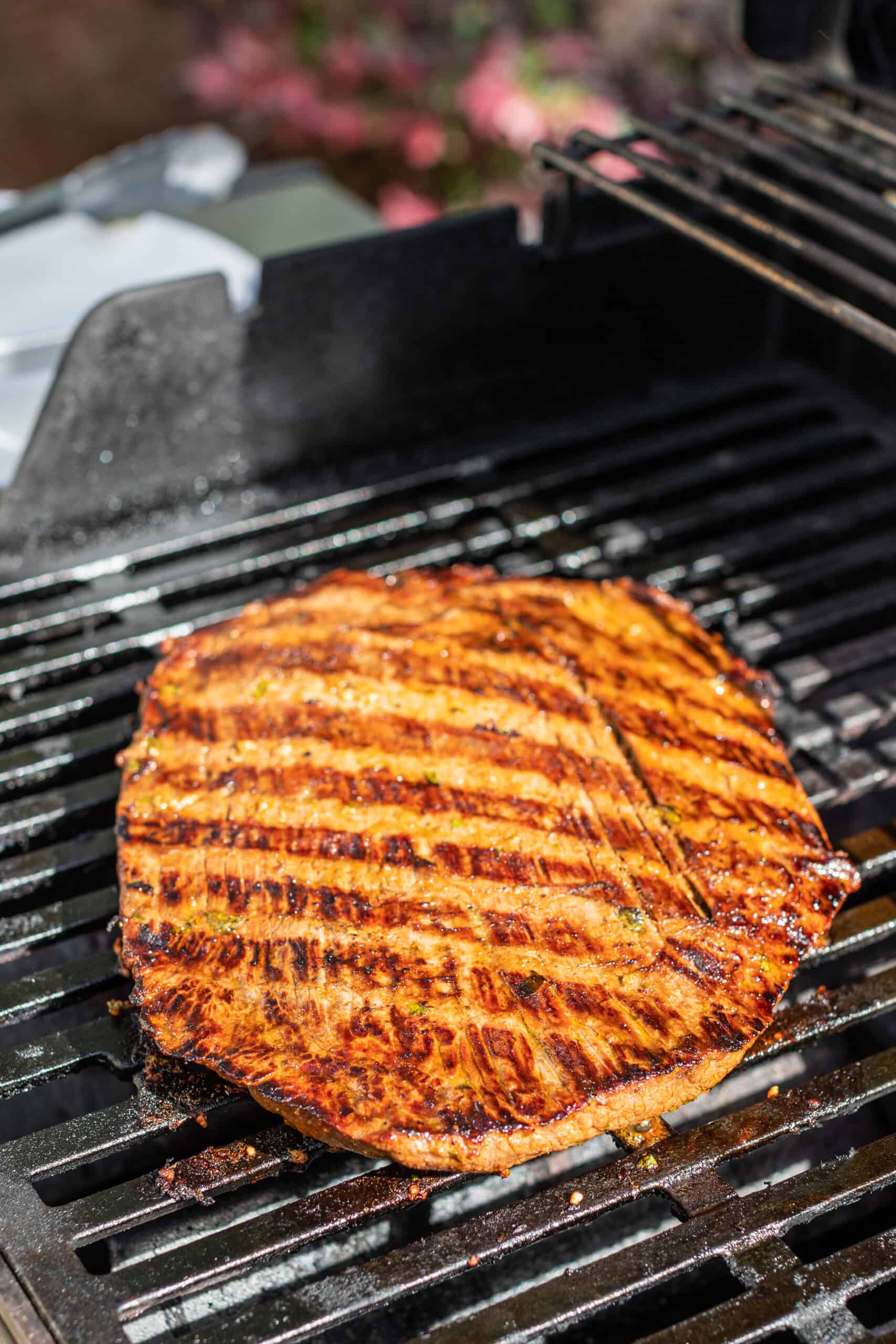 Carne asada flank steak on grill grates.