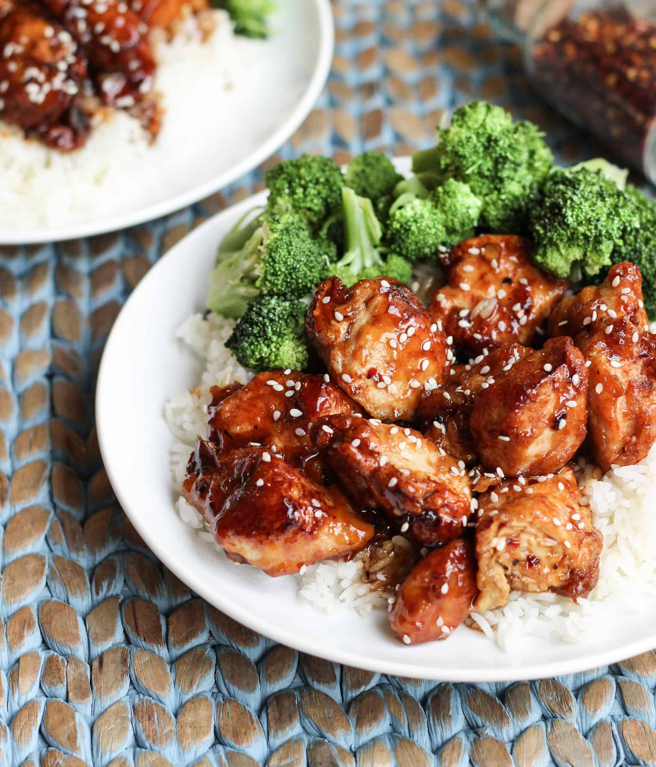 White dinner plate with white rice and glazed sesame seed chicken and broccoli.