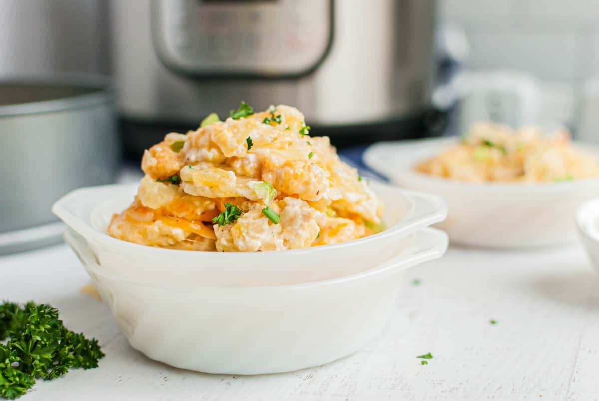 Stack of white dishes filled with cheesy au gratin potatoes.