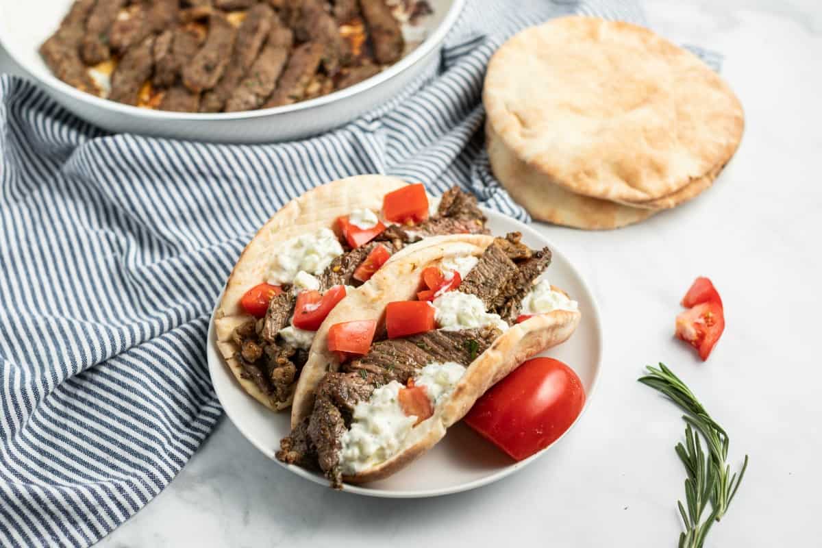 Beef sirloin on two fresh pitas with cucumber sauce and tomatoes.