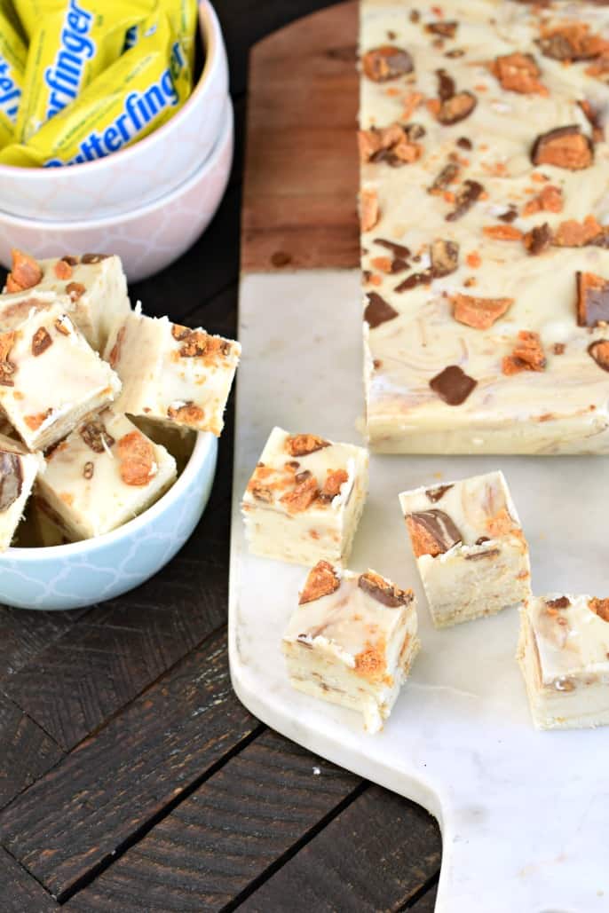 Cutting board with white chocolate fudge and butterfinger candy.