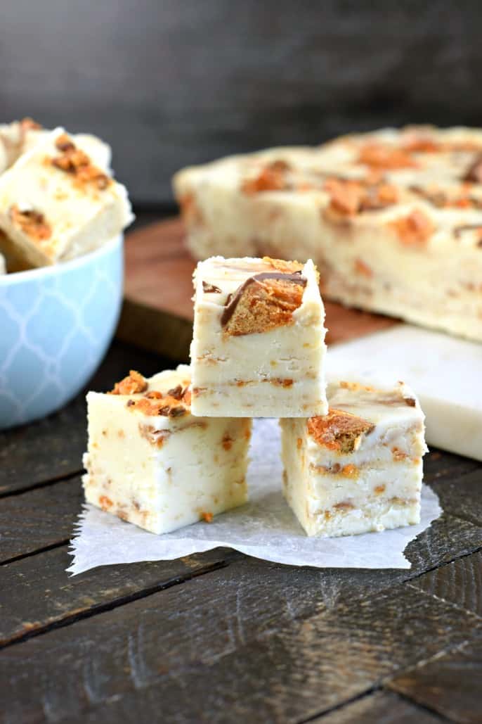 Stack of three pieces of butterfinger fudge on a piece of parchment paper.