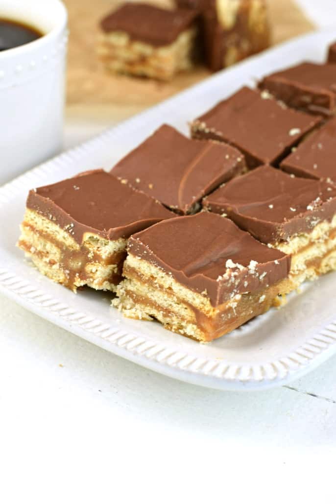 White plate with squares of cracker bars topped with chocolate and oozing with caramel.