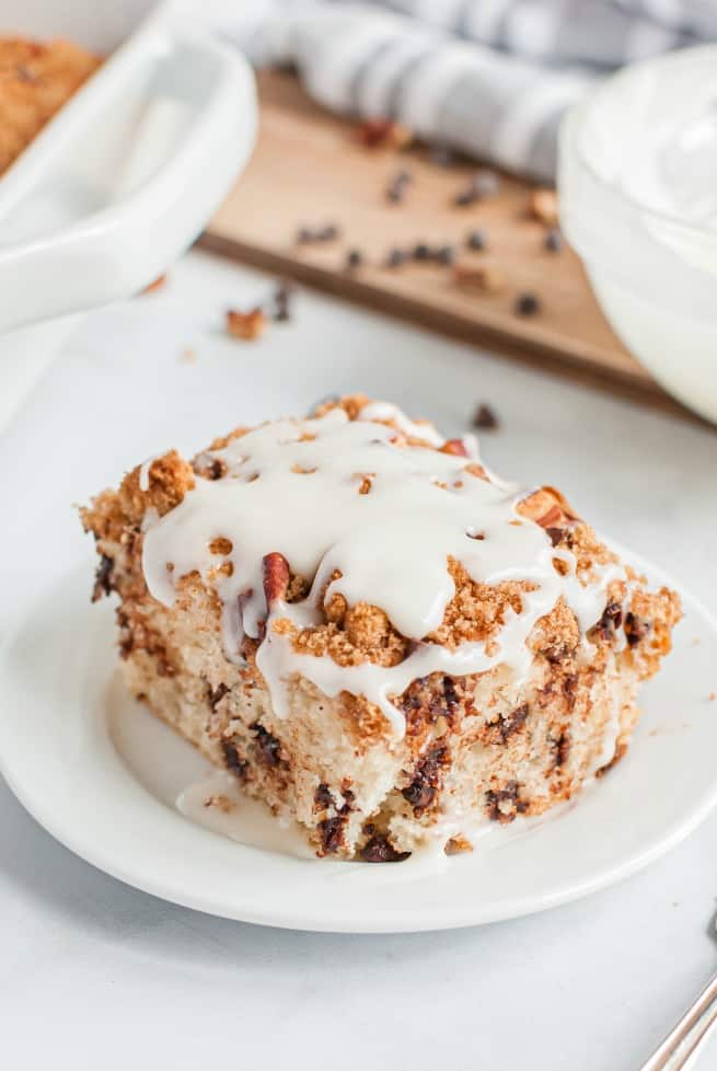 Slice of vanilla glazed Chocolate Chip Cake on a white plate.