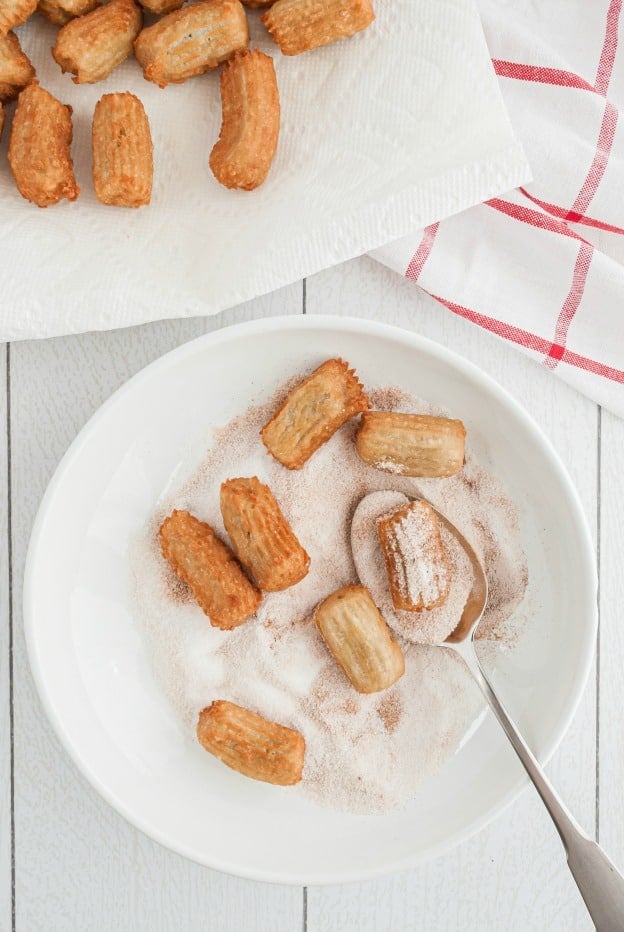 Disney Churro Bites in a bowl of cinnamon sugar mix.