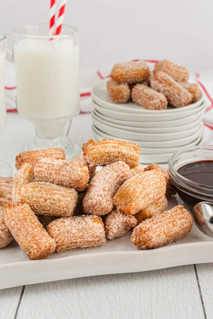 White plate with fried churros and chocolate dipping sauce.