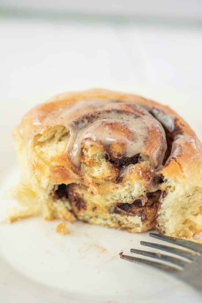 One large cinnamon roll being cut with a fork.