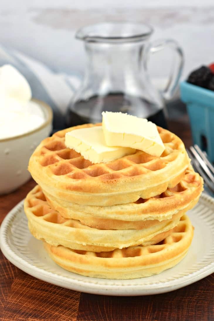 Stack of fresh cooked homemade waffles with two pats of butter. No toppings.