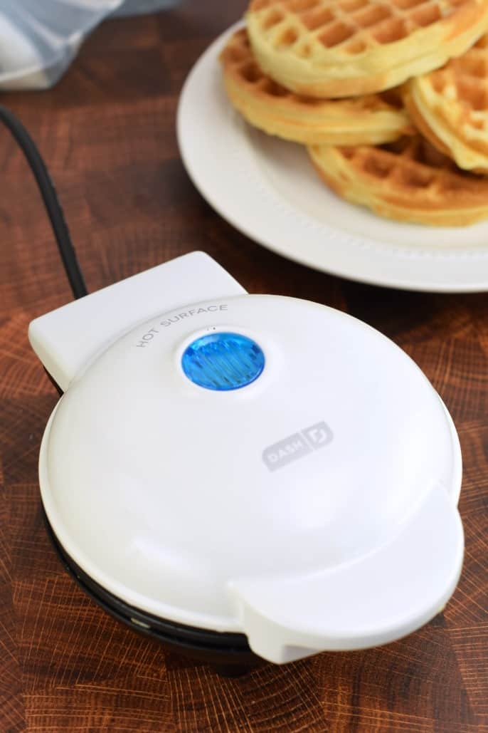 Dash waffle iron with stack of homemade waffles.
