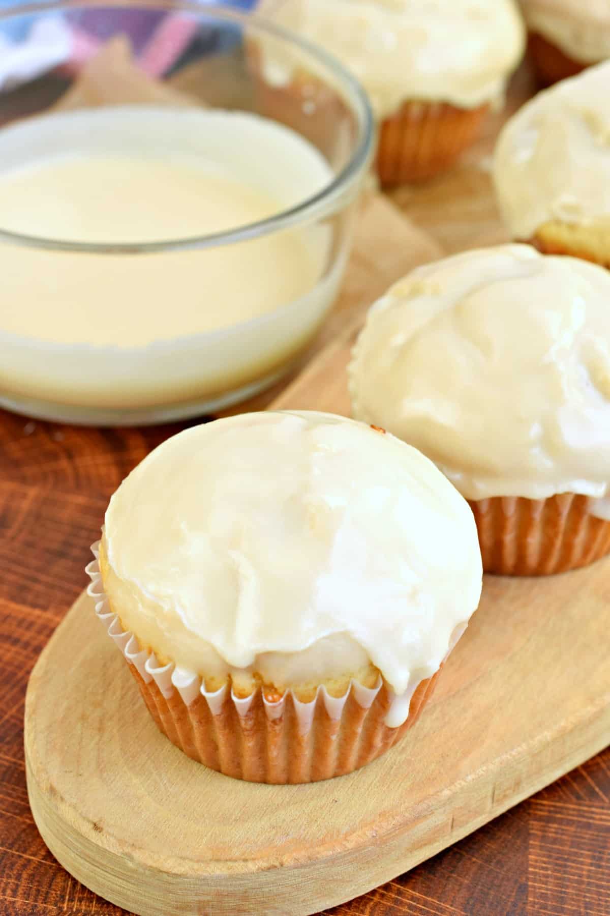Donut muffins with a bowl of vanilla glaze for dipping the tops.