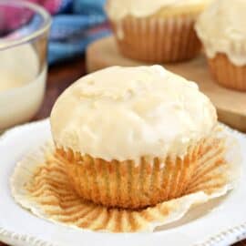 Glazed donut muffin with wrapper peeled off on a white plate.